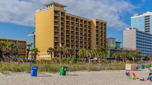 A hotel with multiple floors, balconies, and a beach view.