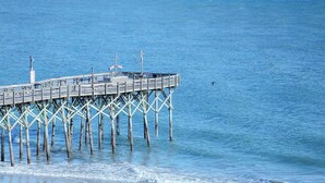 A pier extending into calm blue water with a clear sky.