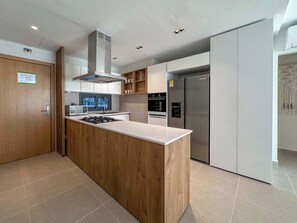 A modern kitchen with a central island, stainless steel appliances, and wooden cabinetry.
