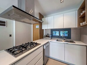 Moderni keittiö, jossa on kaasuliesi, mikroaaltouuni ja sisäänrakennettu astianpesukone.