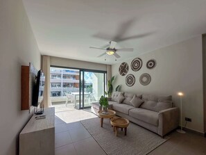 A modern living room with a sofa, a coffee table, a TV, and decorative wall art.