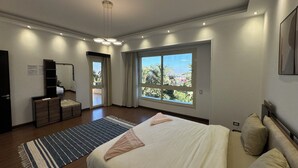 Un dormitorio moderno con una cama grande, vistas de la ciudad y un balcón.