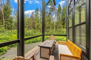 A wooden deck with a table and bench, overlooking a forested area. - Wagon Wheel Hideaway - All season new build home near Tamarack Resort & Lake Cascade (Donnelly)