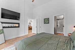 A bedroom with a bed, a TV, a window, and a door leading to a bathroom. - Wagon Wheel Hideaway - All season new build home near Tamarack Resort & Lake Cascade (Donnelly)