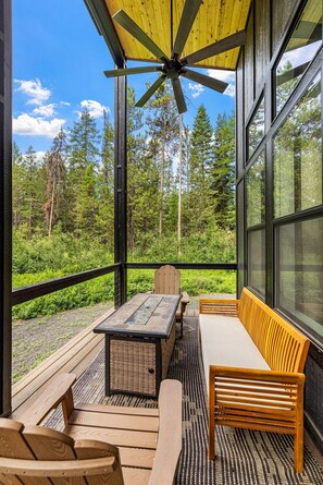 A covered outdoor seating area with a table and chairs, a bench, and a ceiling fan. - Wagon Wheel Hideaway - All season new build home near Tamarack Resort & Lake Cascade (Donnelly)