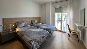 A bedroom with two beds, a nightstand, a chair, and a window with curtains. - Bright & modern 2 bedroom apartment - TR721LT (La Torre Golf Resort)