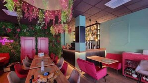 A restaurant with a long wooden table, red chairs, and a neon sign.
