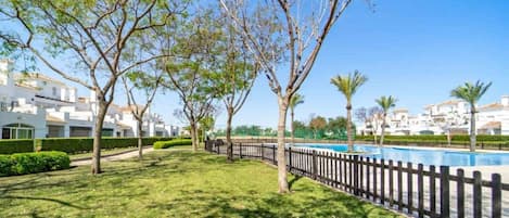 Un área residencial con piscina, árboles y edificios blancos.