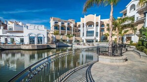 A waterfront hotel with a pool, a curved walkway, and a palm tree. - Bright & modern 2 bedroom apartment - TR721LT (La Torre Golf Resort)