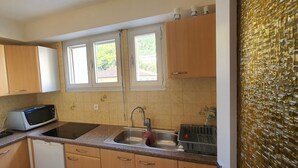 A kitchen with wooden cabinets, a microwave, an oven, a sink, and a window with a view of greenery outside.