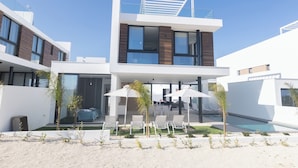 Um edifício moderno de dois andares com piscina, área de estar ao ar livre e um pátio coberto.