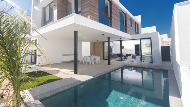 Uma casa moderna de dois andares com piscina, área de estar externa e gramado bem cuidado.