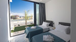 Quarto de hotel com duas camas, uma janela grande com vista para o exterior e design moderno.