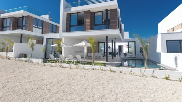 A modern two-story house with a pool, outdoor seating, and a clear blue sky. - Protaras Aqua Pearl Villa Aq10 With Pool Heating (Paralimni)
