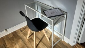 Un espacio de trabajo pequeño y moderno con una silla negra y un escritorio de vidrio.