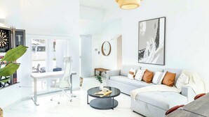 A modern living room with a grey sofa, a round coffee table, and a white desk with a computer.