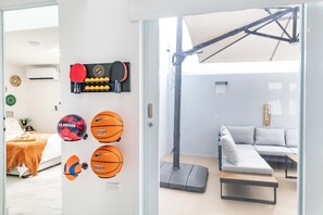 A modern living room with a sectional sofa, a standing lamp, and sports equipment on the wall. - AQUA Casa A/8 Rm 3 · Bedroom in Dorado del Mar (Dorado)