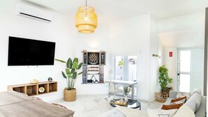 A modern living room with a flat-screen TV, a dining area, and a sofa set.