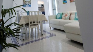 Un salón moderno con un sofá blanco, una mesa de comedor con sillas y un techo con detalles de iluminación azul.