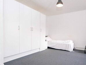 A bedroom with a bed, a wardrobe, and a ceiling light. - 4 Person Holiday Home in Ringkobing (Ringkobing)