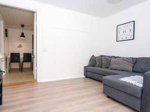 Un salon moderne avec un canapé gris, un coin repas avec deux chaises et un cadre photo fixé au mur.
