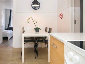 Une cuisine compacte dotée d’un plan de travail blanc, d’une cuisinière et d’un coin repas avec une table et des chaises.