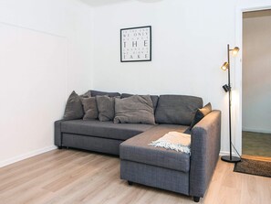 A grey sofa with multiple cushions, a floor lamp, and a framed inspirational quote on the wall. - 4 Person Holiday Home in Ringkobing (Ringkobing)