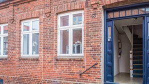A red brick building with white-framed windows and a blue door. - 4 Person Holiday Home in Ringkobing (Ringkobing)
