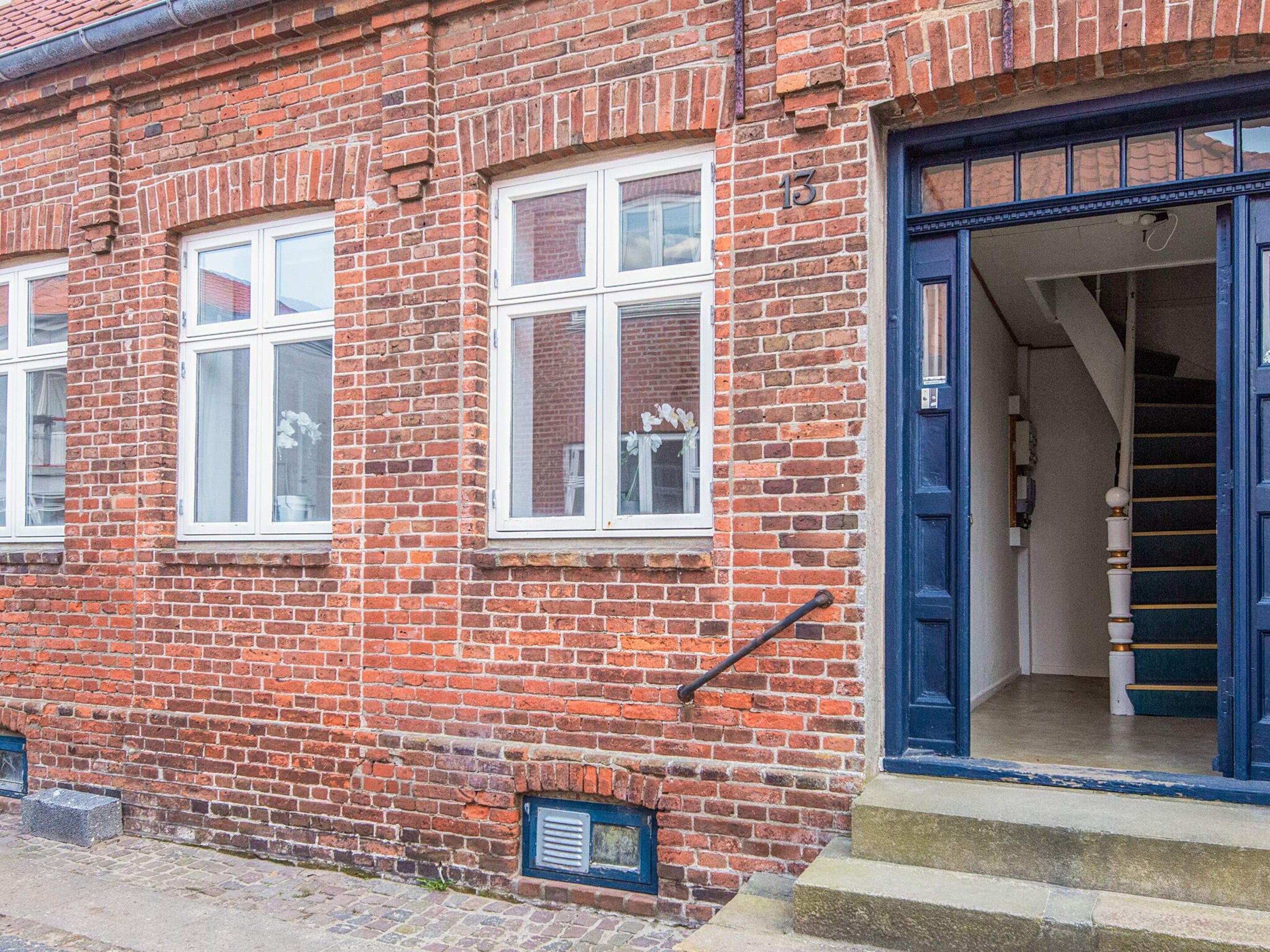 A red brick building with white-framed windows and a blue door.