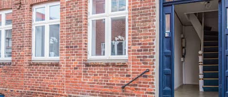 A red brick building with white-framed windows and a blue door.