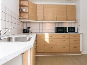 A kitchen with a sink, two microwaves, and wooden cabinets.