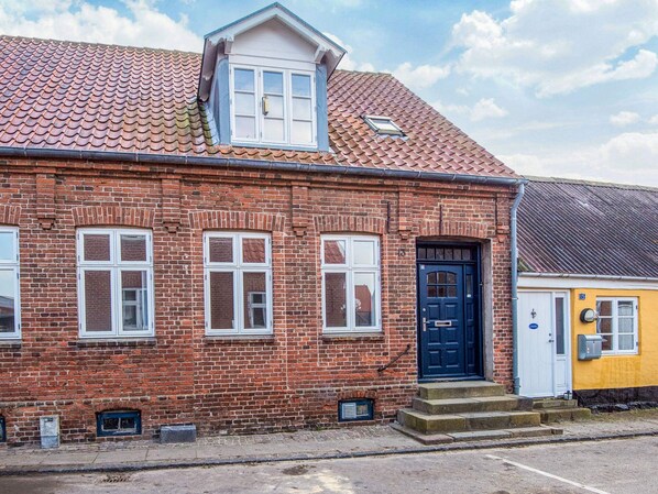 A red brick building with a black door, white windows, and a small porch.