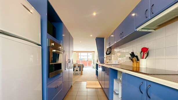 A modern kitchen with blue cabinets, a white countertop, and a built-in oven. - City Center Stay, With Parking (Hobart)