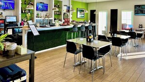 A modern bar area with a green accent wall, multiple TVs, and a variety of liquor bottles.