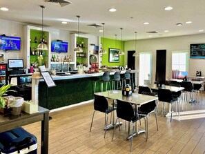 Eine moderne Bar mit einer grünen Akzentwand, mehreren Fernsehern und einer Auswahl an Spirituosen.