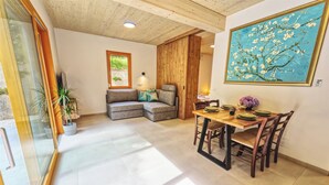 Ein modernes Wohnzimmer mit Holzboden, einem Essbereich mit Holztisch und -stühlen und einem Baumgemälde an der Wand.
