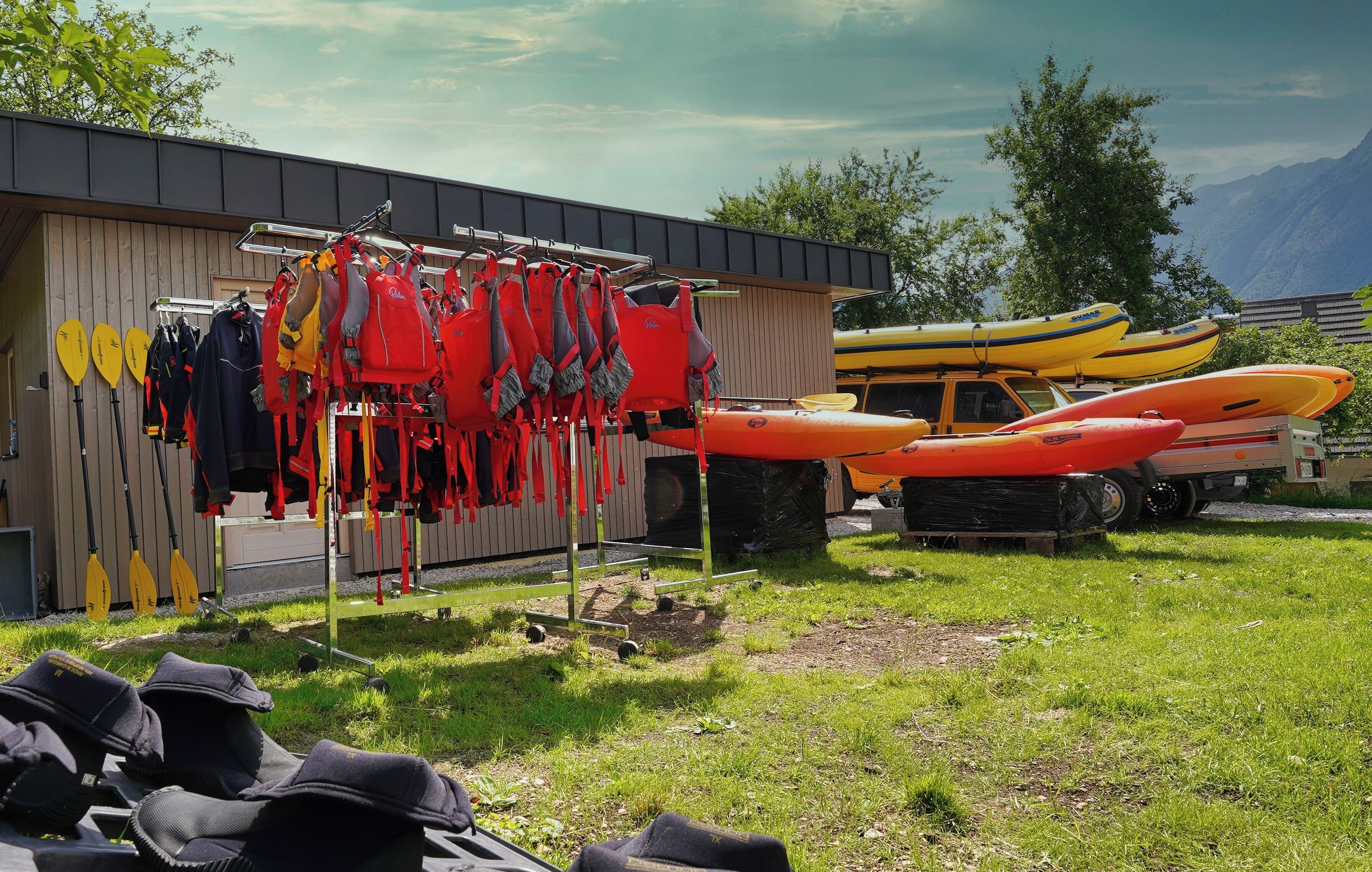 A building with kayaks and life jackets hanging on a rack outside.
