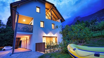 Ein zweistöckiges Haus mit Balkon und sichtbarer Treppe, im Vordergrund ein gelbes Luftboot.