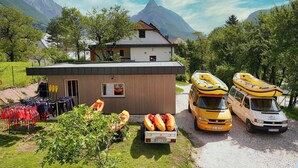 Eine Berglodge mit Kajaks und Rafts, ein kleines Gebäude und ein Van.