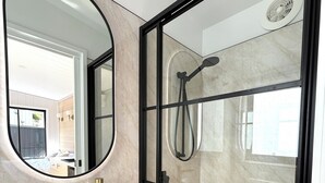 A modern bathroom with a glass-enclosed shower, a white sink, and a large mirror.