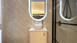A modern bathroom with a toilet, a sink with a mirror, and a glass-enclosed shower area.
