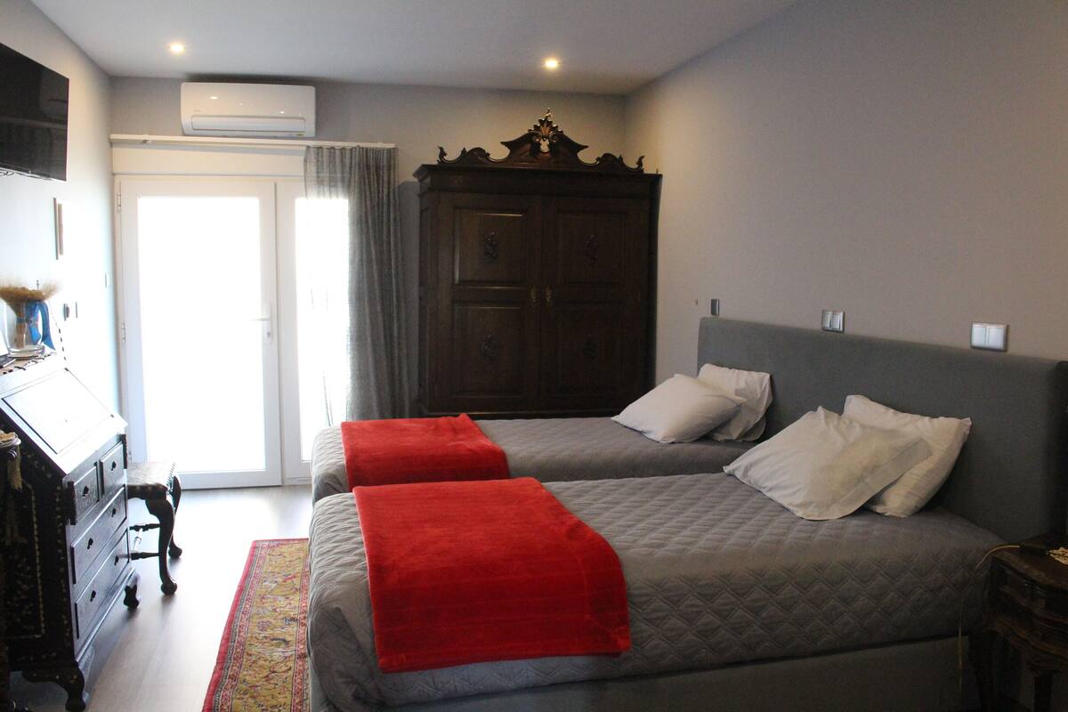 Une chambre d’hôtel avec deux lits, une armoire, un bureau et une fenêtre.