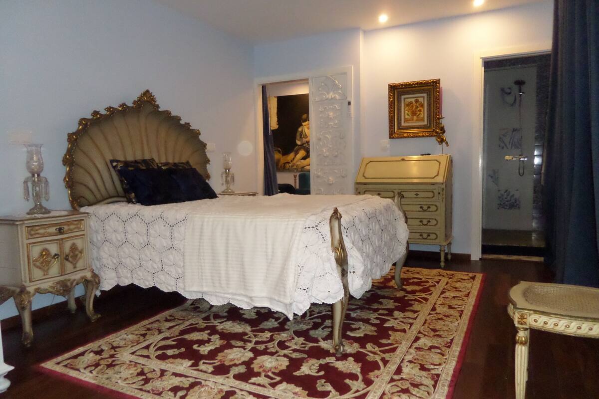 Une chambre à coucher avec un grand lit, une table de chevet, une commode et une chaise.