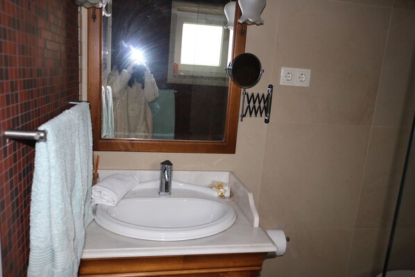 Une salle de bain avec un lavabo blanc, un miroir et un porte-serviettes.