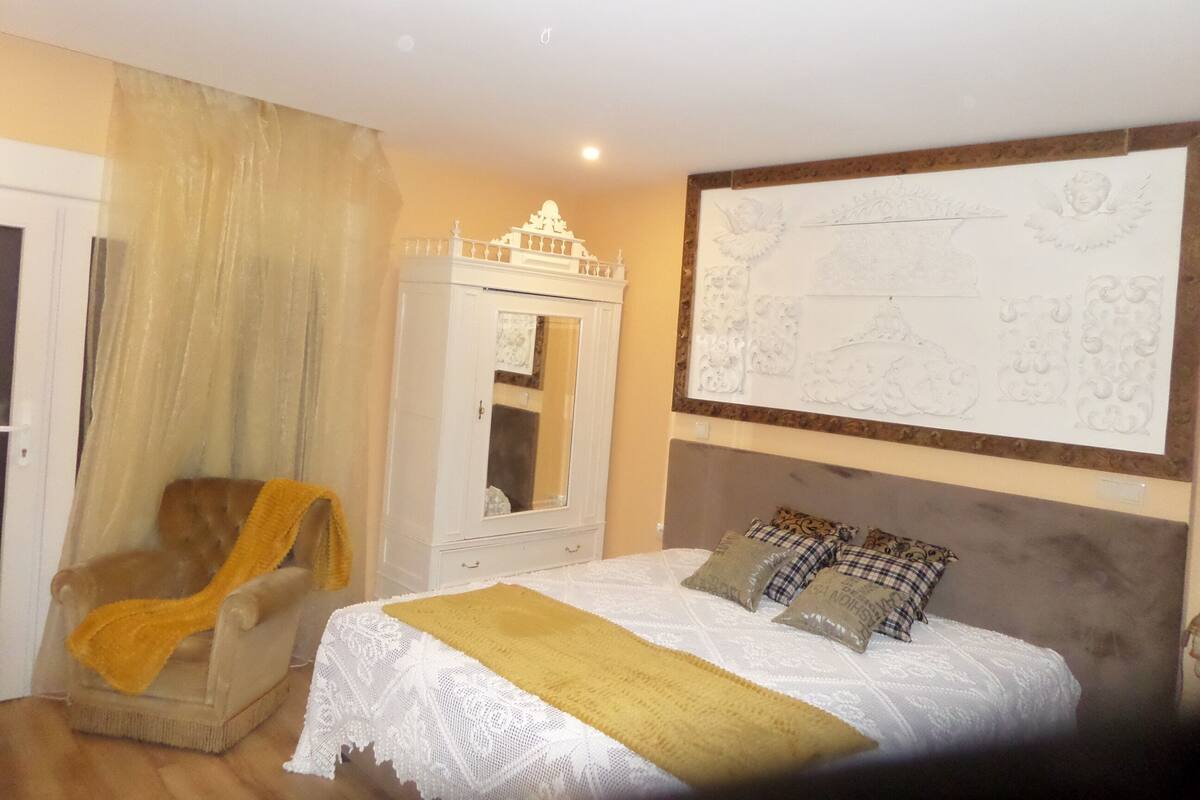 Une chambre à coucher comprenant un lit, une chaise, une armoire et un mur orné d’un panneau décoratif.