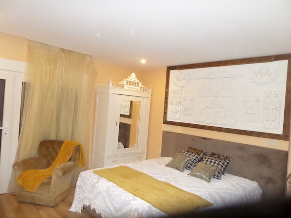 Une chambre à coucher comprenant un lit, une chaise, une armoire et un mur orné d’un panneau décoratif.