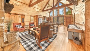 A spacious log cabin interior with a dining area, kitchen, and seating area. - NEW! Prime Cabin Chateau, Hot Tub-Firepit-Sleeps 6 (Broken Bow)