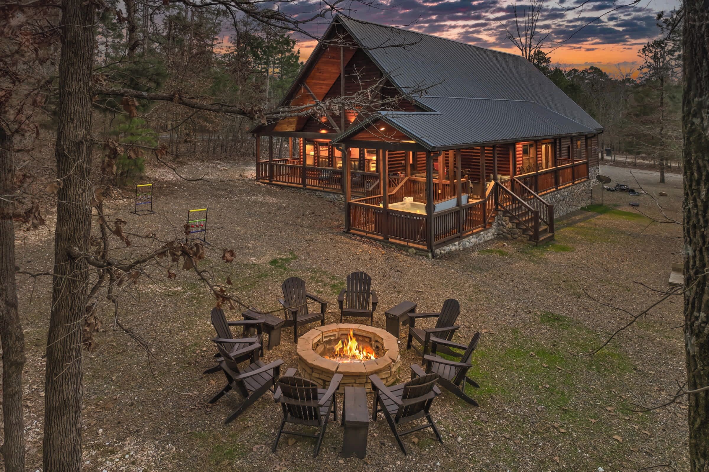 Eine Lodge mit Feuerstelle und Sitzgelegenheiten im Freien, umgeben von Bäumen.