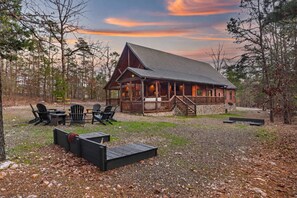 A lodge with a covered deck, outdoor seating, and a stone foundation.