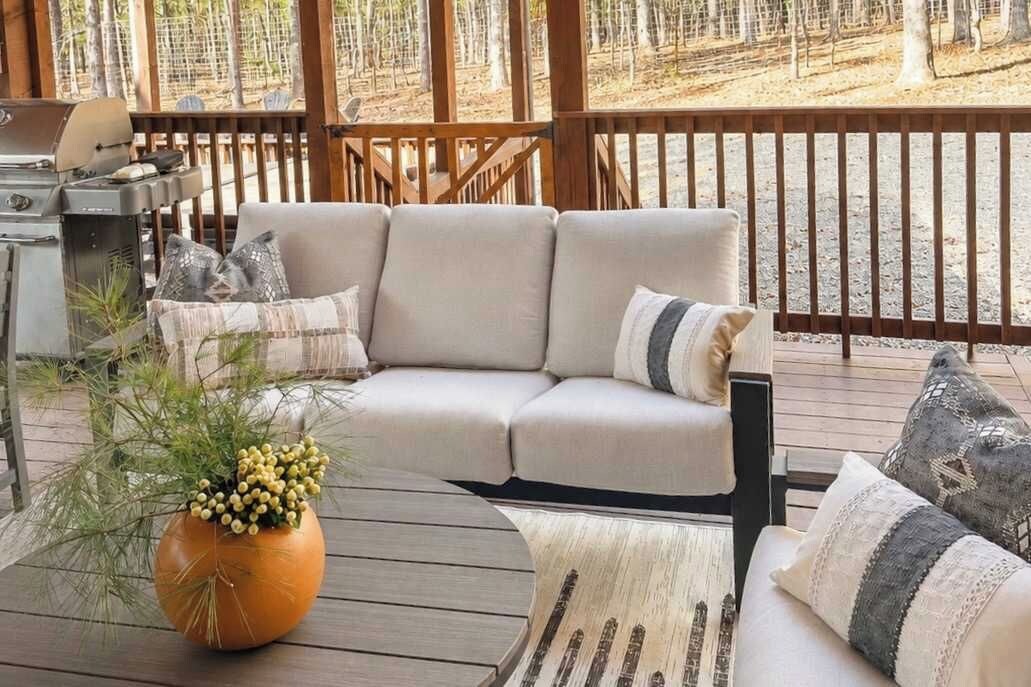 A deck with a sofa, a grill, and a potted plant.